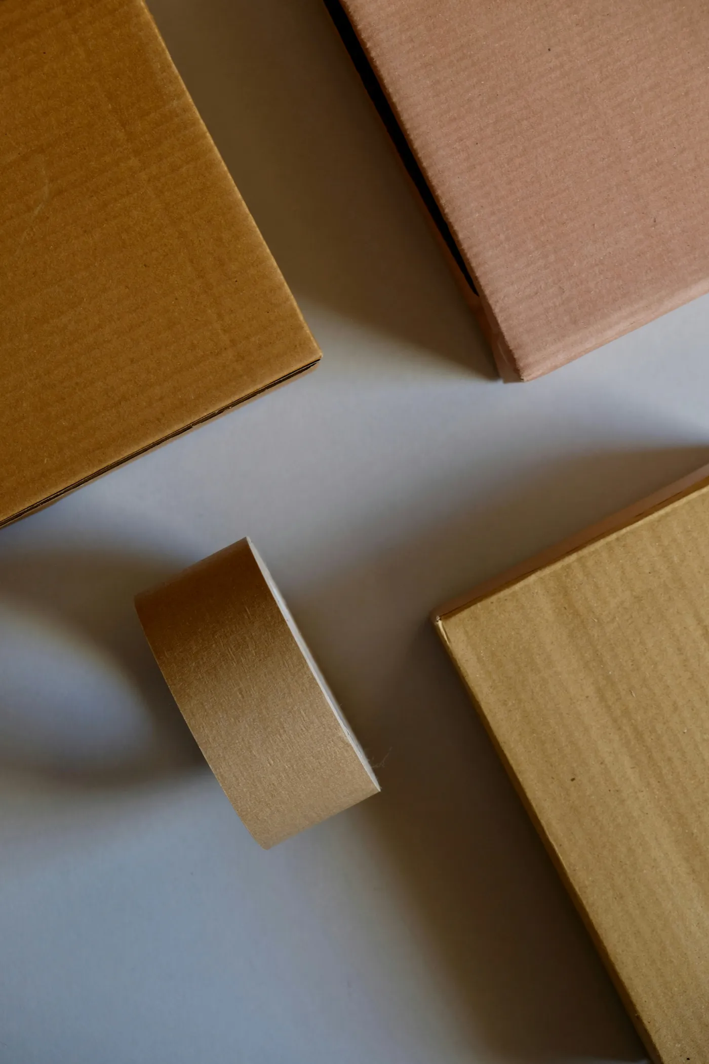 A roll of natural kraft paper tape beside sealed kraft cardboard boxes